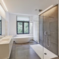 Bathtub in corian, Faucet and shower in tiled bathroom with windows towards garden